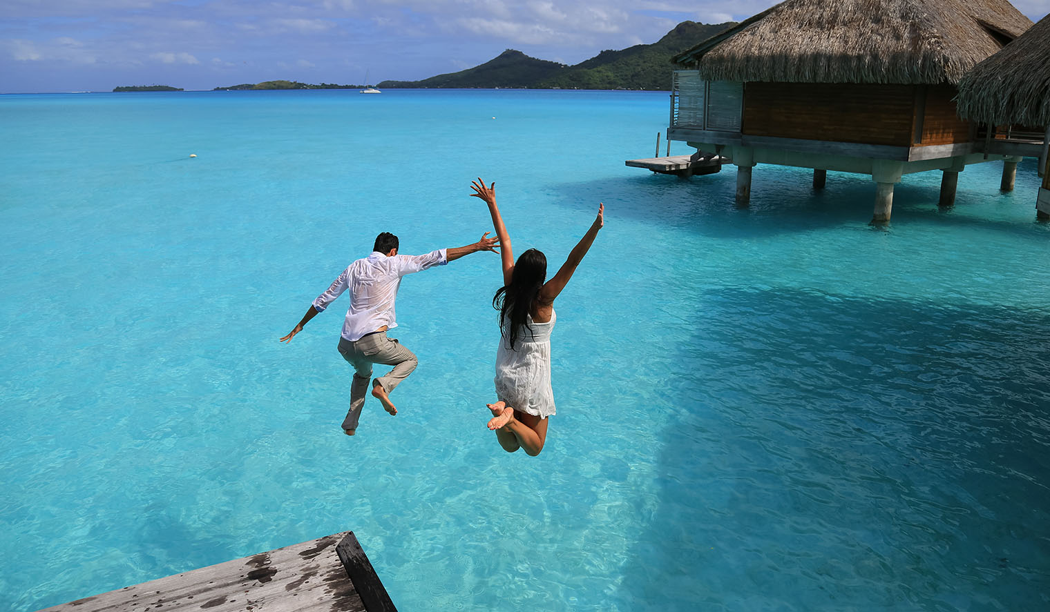 Paar springt von Bungalow in Wasser Honeymoon Polynesien